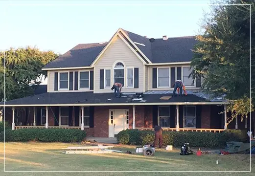 Workers repairing roof of large suburban house.
